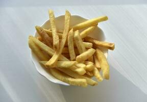 Slices of French fries on a white plate. Delicious fried potatoes. Fast food. photo