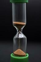 Glass hourglass on a black background. Multicolored glass hourglass. photo