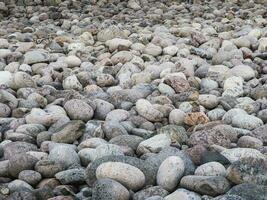 Natural background of pebbles on the seashore close-up. The surface of the beach on the north ocean is covered with large polished round stones of gray color of different sizes. photo