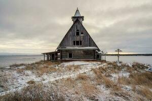 Snowy winter landscape with authentic cinematic house on the shore in the Russian village Rabocheostrovsk photo