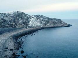 Amazing black pebble beach of Barents Sea coast near Teriberka. Winter on Kola Peninsula, Murmansk Oblast, Russia photo