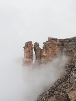 Vertical view of sharp rocks in the fog. Mountains in a dense fog. Mystical landscape with beautiful sharp rocks in low clouds. photo