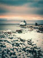 Minimalist snowy winter landscape with authentic wooden house at dusk on the beach in a Russian village Rabocheostrovsk. photo