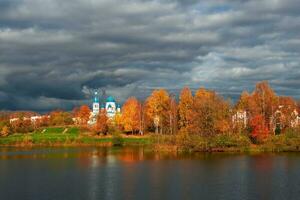 White Cathedral in the distance surrounded by golden autumn trees. Gatchina old city. photo