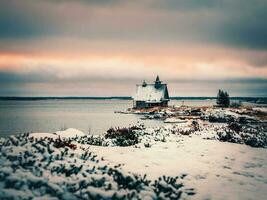 Minimalist snowy winter landscape with authentic wooden house at dusk on the beach in a Russian village Rabocheostrovsk. photo