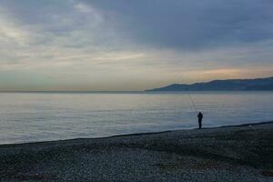 Fisherman at dawn by the sea photo