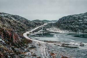 glacial invierno la carretera mediante el tundra colinas en teriberka. increíble vistoso ártico paisaje. foto