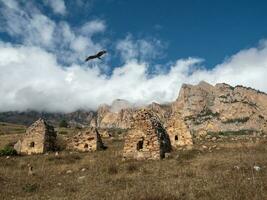 A kite flies over a grave crypt. Old stone tomb, a crypt on the top of a mountain. Old Ossetian family crypt in the misty mountains. photo