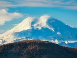 Snowy peak. Scenic landscape with snowy mountain peak in sunny day. Awesome landscape with rocky pinnacle with snow in sunlight. Beautiful view to snow mountain top of Elbrus. photo