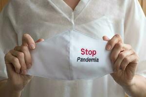 Medical mask in a hand and sign Stop Pandemia photo