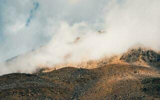 blanco nube descendió en el rojo montaña picos ligero en el Mañana montañas. brillante soleado natural Montaña alta antecedentes. foto