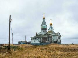 de madera auténtico kashkarantsy iglesia. un pequeño auténtico pueblo en el blanco mar costa. kola península. foto