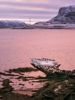 An old rusty fishing boat abandoned by a storm on the shore. Graveyard of ships. photo