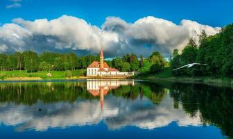 Bright beautiful panoramic spring landscape with peaceful lake, dramatic sky and a old white Maltese castle. Gatchina. photo