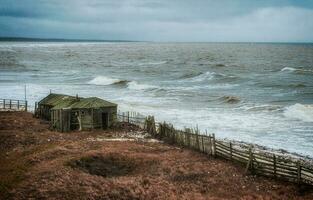 Dramatic seascape with a raging White sea and a fishing hut on the shore. Kandalaksha bay. Umba. Russia photo