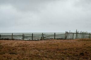 Old fishing fence on the background of a dramatic sky on the beach photo