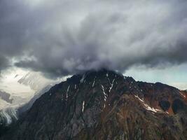 Wonderful dramatic landscape with big snowy mountain peaks above low clouds. Atmospheric large snow mountain tops in cloudy sky. photo