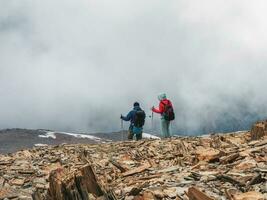 A man and a woman climb to the top of a misty snow hill. teamwork and victory, teamwork of people in difficult conditions. A difficult climb to the top of the mountain. photo