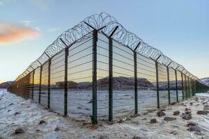 A corner of a fence with barbed wire on the background of the evening sky in an Arctic village. photo