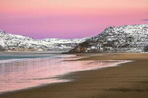 Amazing sunrise polar landscape with white snowy mountain range on the horizon. Arctic ocean view. photo