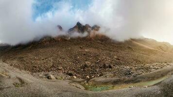 atmosférico Mañana montaña paisaje. panorámico paisaje en tierras altas. agudo picos de el rocas Mira fuera desde el nubes y Mañana niebla. foto