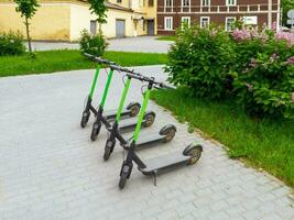 dos ciudad scooters en el asfalto. cuatro estacionado scooters en el verano ciudad. moderno juventud modo de transporte. foto