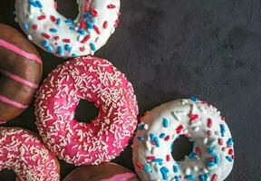 Colorful donuts on black stone table. Top view photo