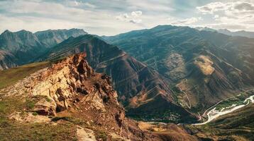 Colorful summer landscape with silhouettes of big rocky mountains and epic deep gorge with river.The edge of a rocky cliff with a beautiful panoramic view of the gorge. photo