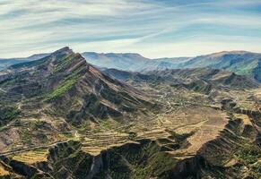 montaña valle. un rocoso repisas extensión dentro el distancia en contra el antecedentes de montañas cubierto con escaso vegetación. foto