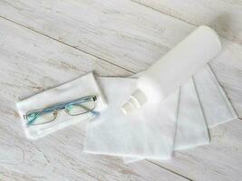 Disinfection of glasses concept. Cleaning protection glasses with alcohol spray and wipe out with cleaned paper photo