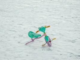 Abandoned broken children's bike in the snow. The end of the holidays. photo