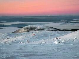 Beautiful Arctic sunset. Scenic colorful sky at dawn. Winter time. Cabin in winter. Dubldom on the mountain Volosyanaya Kandalaksha, Murmansk region in Russia. photo