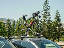 Car is transporting black bicycle on the roof. photo