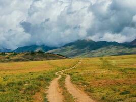 Way to the distance, way over the hill to the sky. Dirt road through the field. Atmospheric foggy mountain scenery with length road among hills. photo