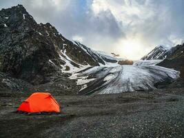 An orange reinforced tent against the background of a glacier on a high-altitude plateau. photo