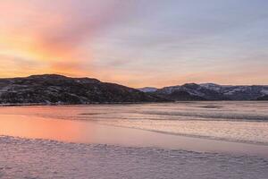 An ice-covered mountain lake. Magic Magenta sunset on a mountain North of the lake. photo