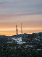 Cell towers in the snow-covered hills in tundra. Beautiful sunset hilly landscape of the Arctic. photo