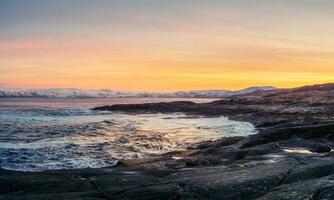 A rock cliff with a tidal shoreline. Wonderful panoramic mountain landscape on the Barents sea. photo