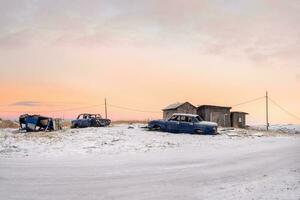 Arctic evening rural landscape. Old disassembled car at the garages in authentic village of Teriberka. Kola Peninsula. photo