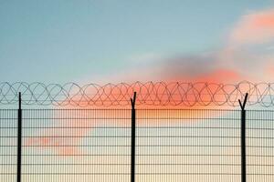 Wire mesh fence with colorful sky background. photo