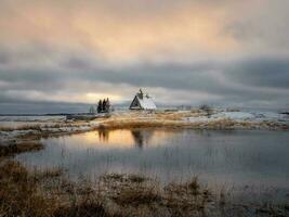 Beautiful evening winter landscape with a small authentic wooden house at dusk on a cliff. photo