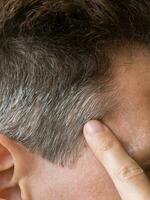 un dedo señalando a el gris pelo en su cabeza. foto