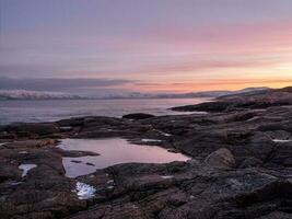 maravilloso montaña paisaje con un capa en el apuntalar de el Barents mar. increíble amanecer paisaje con polar blanco Nevado rango de montañas. foto