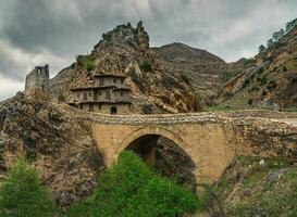 Dramatic mountain scenery with old stone bridge in dark rainy day. photo