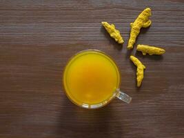 Herbal tea with turmeric powder and turmeric roots on a brown table photo