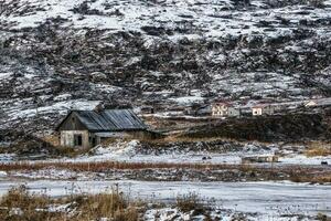 caza abandonado presentar en un ártico cubierto de nieve colina. antiguo auténtico pueblo de teriberka. kola península. foto