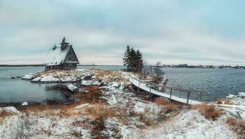 Snowy winter landscape with authentic house on the shore in the Russian village Rabocheostrovsk. photo