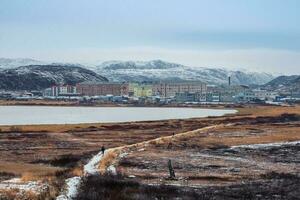 A narrow path that goes into the distance to the Arctic village located between the polar hills. photo