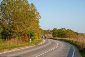 Asphalt highway country road among beautiful autumn hills with cottages photo