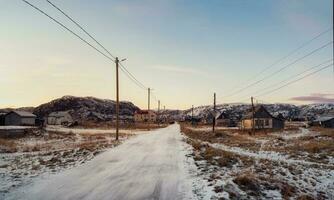 Vintage houses on the background of snow-covered Arctic hills. Old authentic village of Teriberka. Kola Peninsula. photo